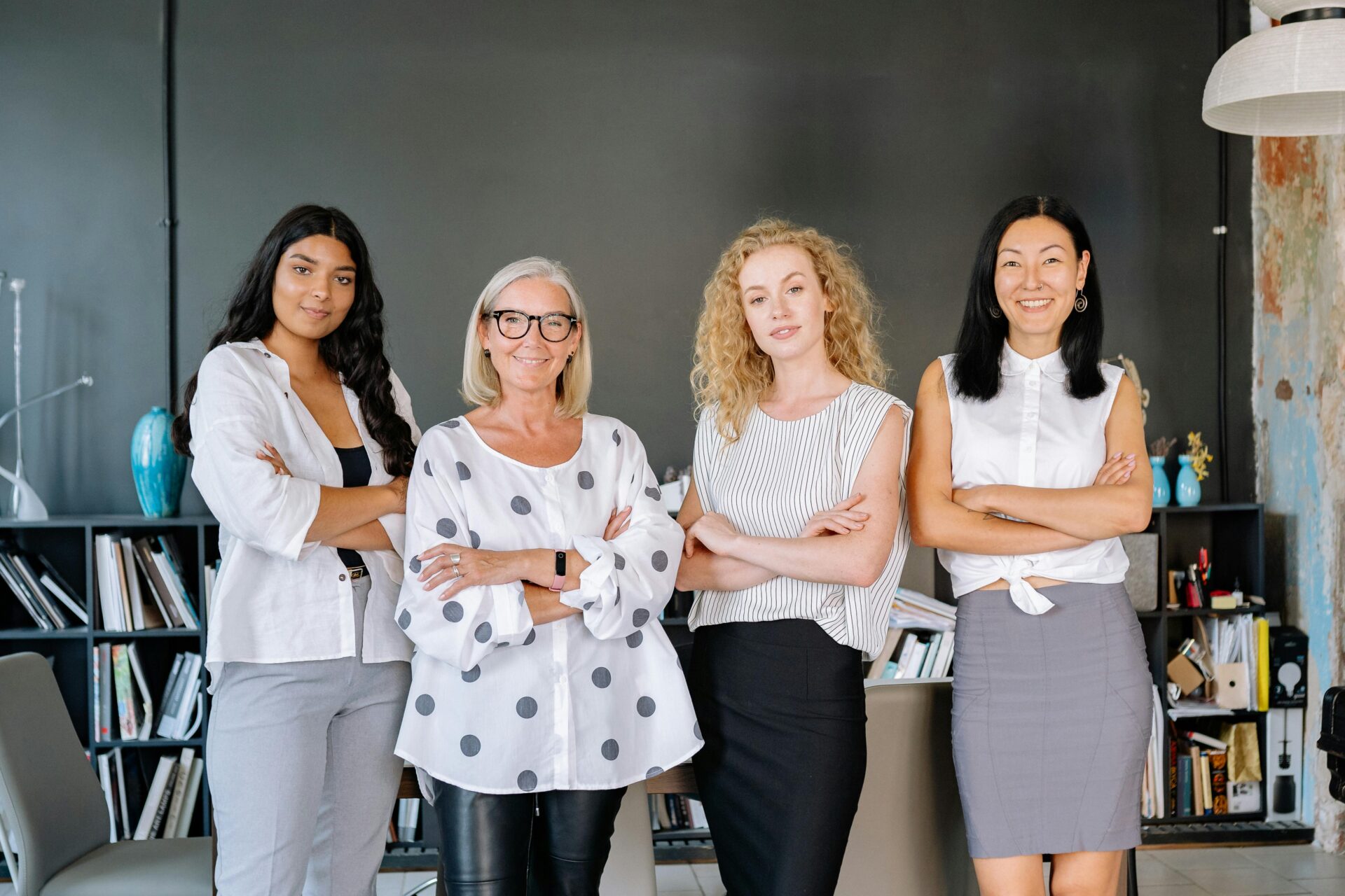 Four women with their arms crossed standing in a row.