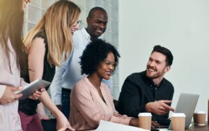 Diverse group of colleagues gathered around a laptop sharing ideas