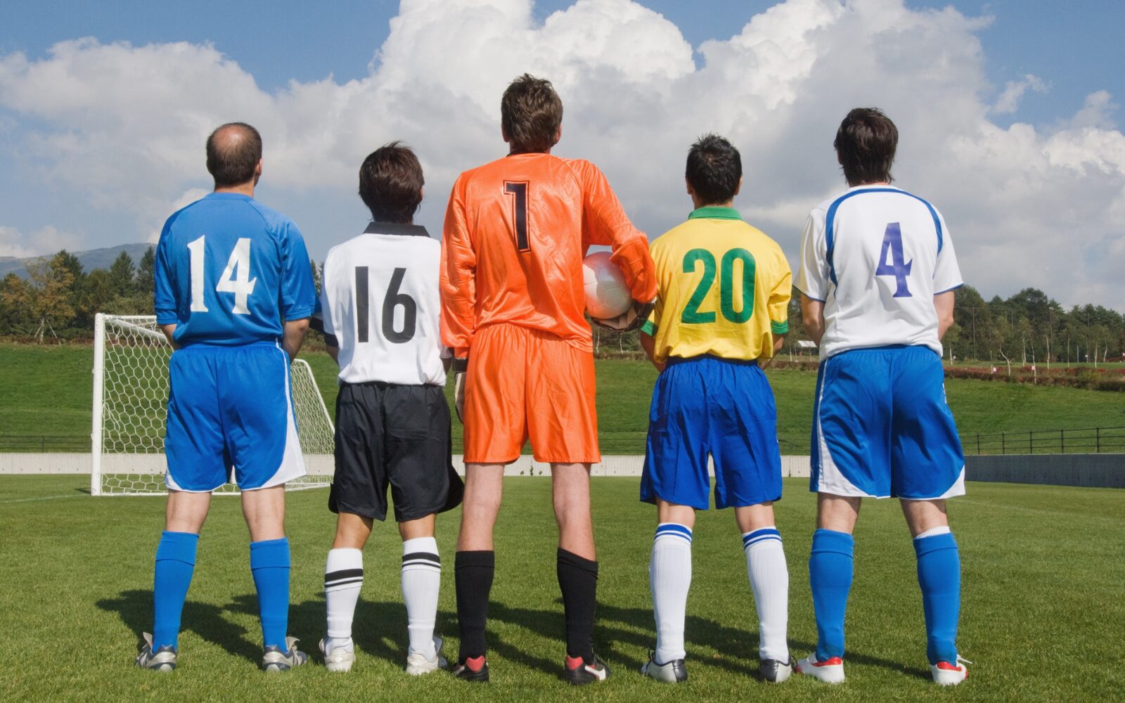 A shot standing behind a group of footballers each wearing a different uniform