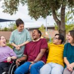 A group of friends laughing and sitting outside, enjoying the sun