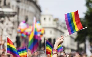 A shot of a hand waving the LGBT+ pride flag at a pride celebration