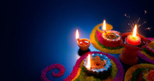Oil lamps lit on colourful rangoli during Diwali Celebrations.