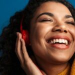 Happy black women with her eyes close, holds onto her headphones.
